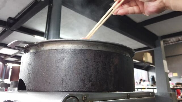 Traditional Thai barbecue grill pan, known as Moo Kratha, with a piece of pork lard melting on top. Popular Thai-style BBQ combining grilling and hotpot cooking in one pan.