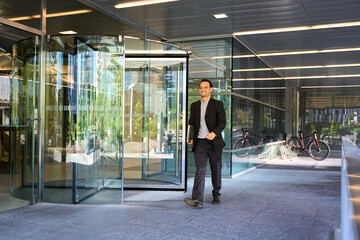 Fototapeta premium Confident latin businessman exiting modern office building