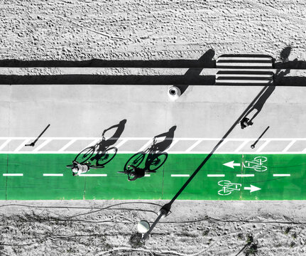 Aerial view of cyclists gliding along a vibrant green bike path, contrasting sharply with the surrounding urban landscape, Tel Aviv-Yafo, Tel Aviv District, Israel.