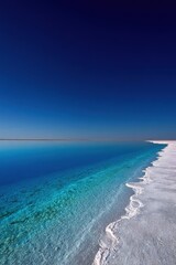 Azure Water Meets White Shoreline Under Sunny Sky