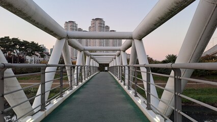Modern pedestrian bridge with geometric structure leading toward city buildings