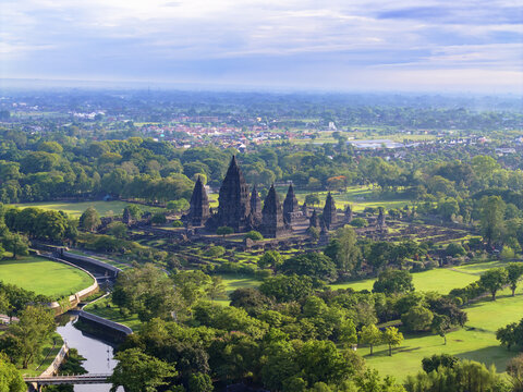 Aerial view of the magnificent Prambanan Temple rises majestically amidst a sea of verdant trees under a vast expanse of sky, Yogyakarta, Daerah Istimewa Yogyakarta, Indonesia.