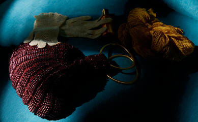 Handbag, gloves, and scarf.

On a dimly lit surface, you can see a woman's handbag with glittery details, a pair of openwork gloves, a mustard-colored neck scarf, and a perfume bottle.