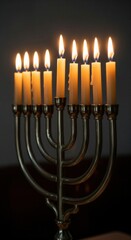 Fototapeta premium A classic Hanukkah menorah with all nine candles lit, glowing against a simple dark background. This clean image captures the quiet, spiritual moment of the holiday ritual of faith.