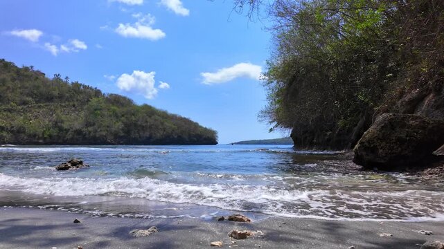 Captivating vista of tropical beach under gentle breeze, where turquoise waters meet black sands, showcasing breathtaking beauty of Indonesia natural paradise