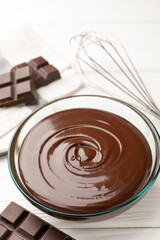 Melted chocolate, whisk and pieces white on wooden table, closeup