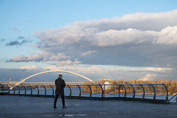 Man standing on embankment with view of Podilskyi bridge in Kyiv