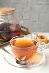 Tasty tea in glass cup, teapot and Turkish desserts on white table against grey textured background, closeup