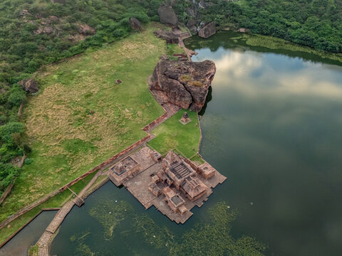 Aerial view of the Bhutanatha temple complex standing in stark contrast to the still waters of the lake, cradled by rugged hills, Badami, Karnataka, India.