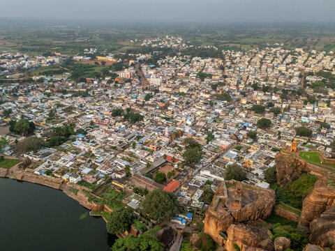 Aerial view of a sprawling cityscape nestled amidst rugged terrain, where ancient stone structures meet modern dwellings, creating a tapestry of history and life, Badami, Karnataka, India.