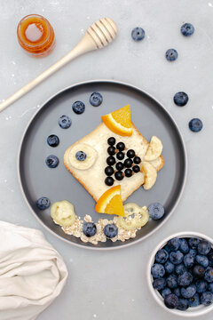 Naklejki Funny cute sandwich toast bread.Kids childrens baby's dessert healthy breakfast lunch food art like fish with fruits,blueberry,wooden background close up,top view