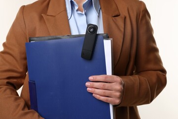 Businesswoman with hidden spy camera and clipboard on white background, closeup