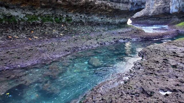 Serene water visuals depict tidal shifts in rocky cave, emphasizing harmony of ocean life, revealing Indonesia hidden marine treasures, slow motion