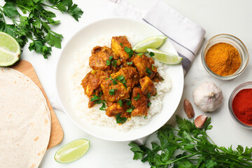 Chicken tikka masala with rice served on white marble table, flat lay