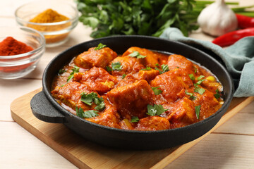 Chicken tikka masala with spices on light wooden table, closeup