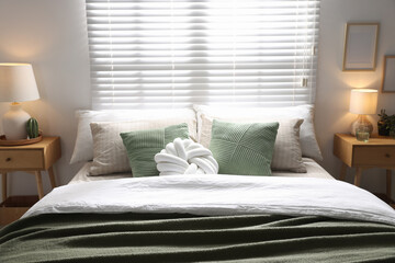 Stylish bedroom with large bed, pillows and lamp. Interior design