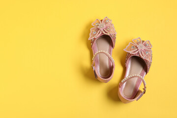 Pair of stylish kid's shoes on yellow background, flat lay. Space for text