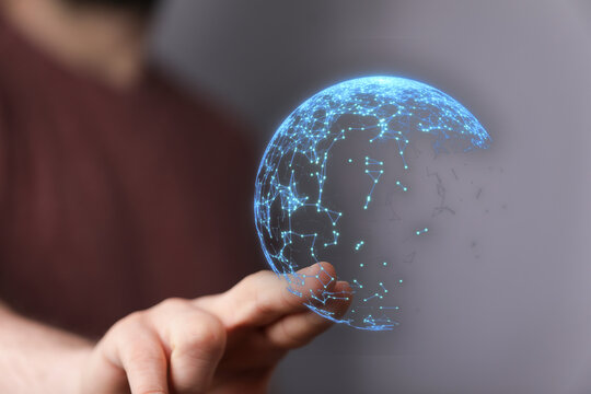 Abstract image of a person holding a glowing digital globe, representing global communication, network connections, and data transfer. Suitable