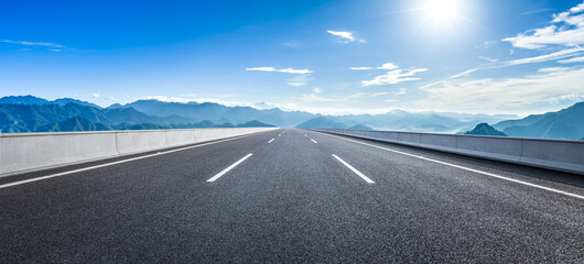 Empty asphalt highway road and green mountain natural landscape under a beautiful blue sky with clouds