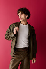 Stylish man in modern attire poses confidently against a vibrant pink backdrop