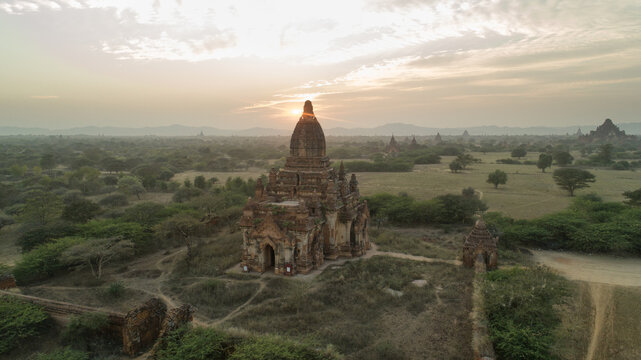 Aerial view of ancient temples piercing through the golden haze of dawn, casting long shadows across the Bagan plains, Old Bagan, Mandalay Region, Myanmar.