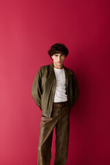 Obraz premium Handsome man showcases stylish outfit against vibrant red backdrop in modern setting