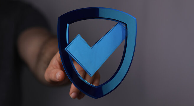 A hand presenting a 3D shield with a check mark, representing protection, security, and assurance in a digital world. Perfect for cyb