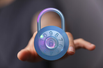 Close-up of a hand holding a glowing padlock. The image symbolizes security, data protection, and...