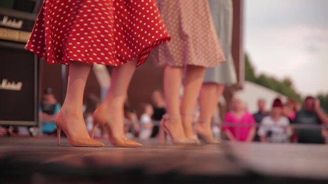 Dancers In Polka-Dot Skirts And High Heels Perform A Kick Line On Stage. Womens Legs In A Synchronized Dance At A Retro-Themed Event.