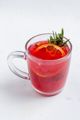 A vibrant herbal tea with orange slices and rosemary offers a colorful, aromatic experience