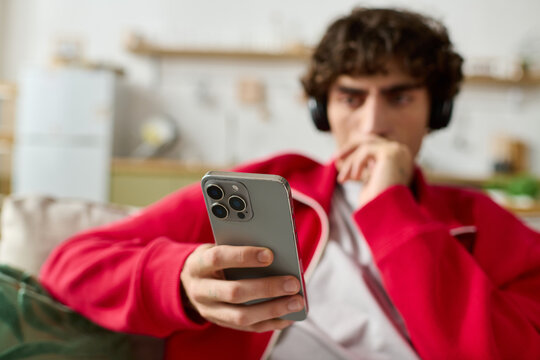 Stylish man enjoying time at home while using his smartphone and listening to music