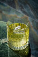 A vibrant green cocktail in a crystal glass rests on a marble surface, inviting enjoyment