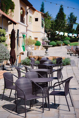 Outdoor synthetic rattan chairs and coffee table set up in front of a cafe, creating a relaxing spot for tourists to unwind.
