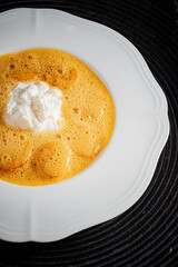 A delightful creamy dish with frothy texture sits on a white plate, inviting taste