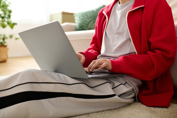 Naklejka premium Stylishly dressed man relaxes while working on a laptop in a cozy indoor setting