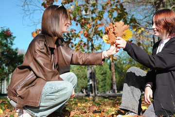 Obraz premium mother and teen daughter collecting autumn leaves in the park