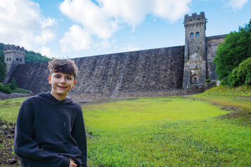 Happy boy by ancient Howden dam and grassy landscape , England