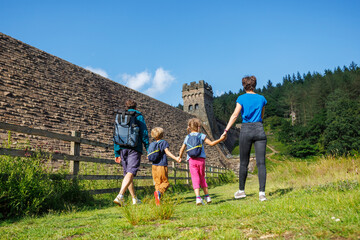 Happy family walking near scenic Howden dam with forest backdrop