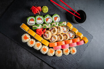 Colorful sushi rolls with wasabi and pickled ginger, elegantly arranged on a dark surface