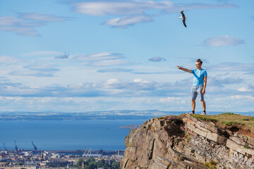 Man hiker pointing at city on the top of Arthurs Seat, Edinburg