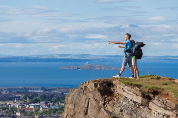 Two hikers marvel at expansive views from a grassy cliff edge