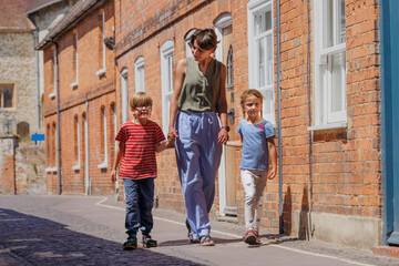 Woman walking with two kids by brick buildings in Farnham, UK
