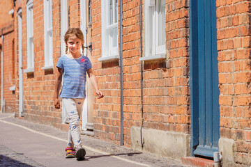 Girl walking by brick wall on sunny day in historic city Farnham
