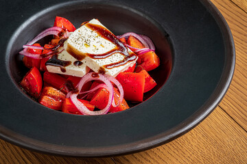Vibrant salad bursting with color, featuring juicy tomatoes and crispy onions topped with feta