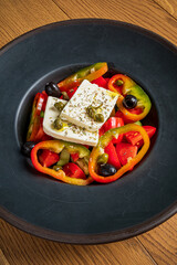 A vibrant salad features feta cheese, various peppers, and olives arranged beautifully