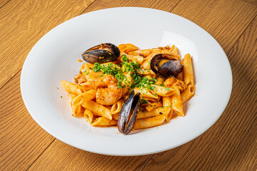 A flavorful seafood dish featuring pasta, shrimp, mussels, and fresh herbs on a wooden table