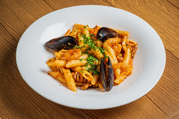 Colorful seafood pasta with mussels and shrimp, topped with fresh herbs on a wooden table
