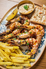 Grilled shrimp with golden fries, a tasty dip, and a lemon slice garnish