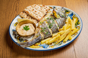 Grilled fish with seasoned rice, golden fries, and soft flatbread on a vibrant platter