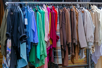 Colorful modern clothes on metal rail sold outside on local market